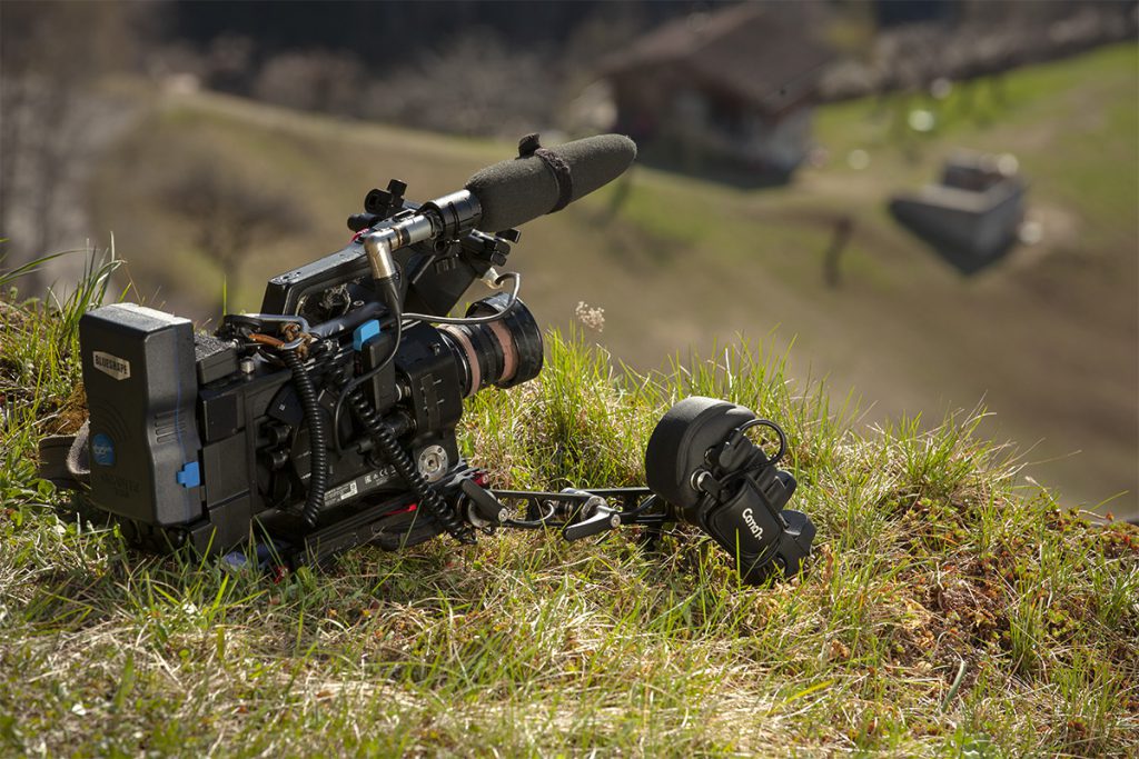 Caméra Sony FS7 II posée dans l'herbe, connectée à une poignée de commande Caman S GRIP PRO