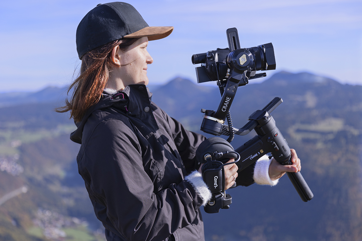 Femme sur le Mont d'Or qui filme avec une caméra Sony Z90 ou AX700 montée sur un stabiliseur Zhiyun Crane 3 et contrôlée avec la poignée Caman S GRIP PRO